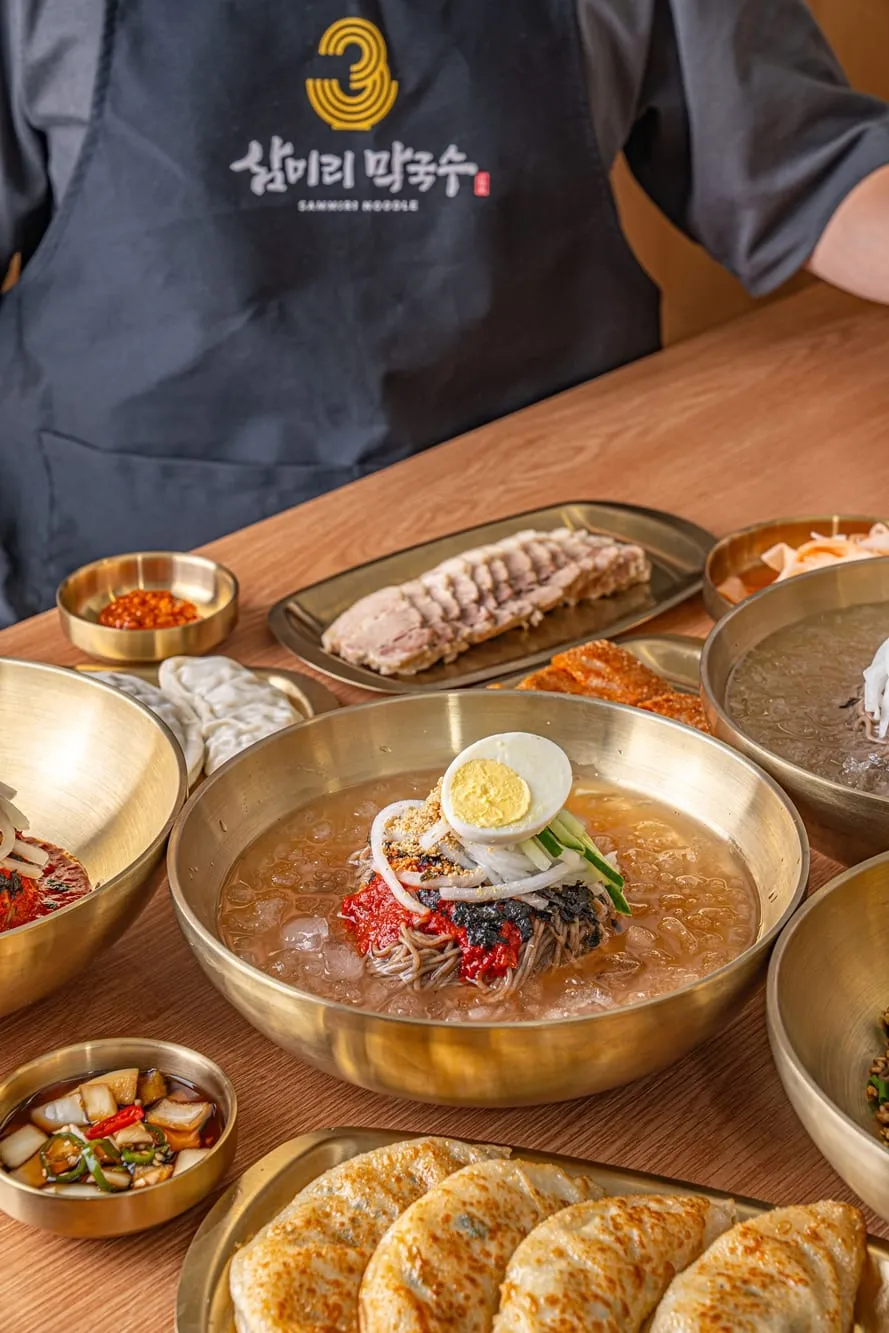 삼미리막국수 앞치마를 입은 직원이 상을 차리는 모습